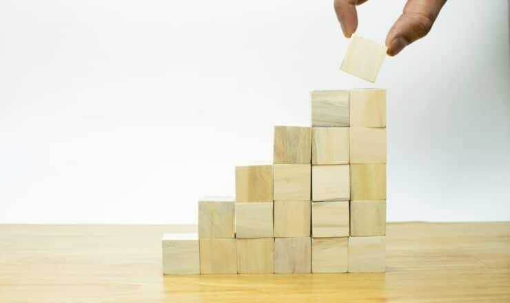 A person placing a piece of wood into a pyramid