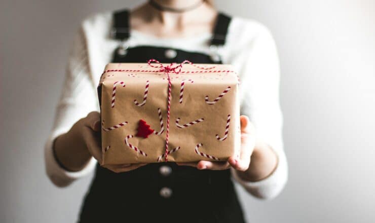 tilt-shift lens photography of woman holding candy cane-print gift box in a well-lit room
