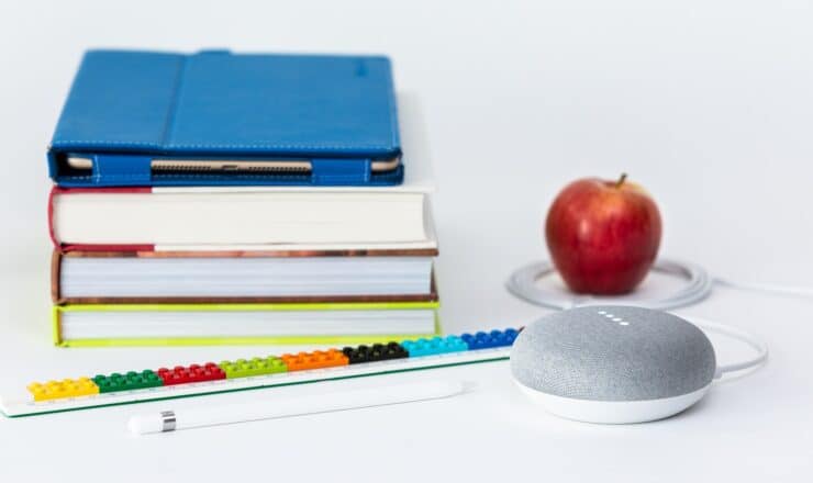 honeycrisp apple fruit near books and chalk Google Home Mini smart speaker