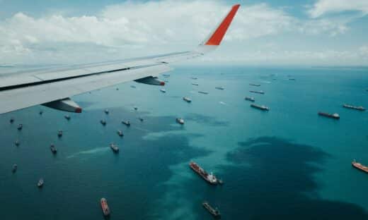 white and red airplane wing over the sea during daytime