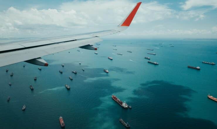 white and red airplane wing over the sea during daytime