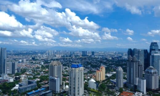Cityscape under a bright blue sky with fluffy clouds.