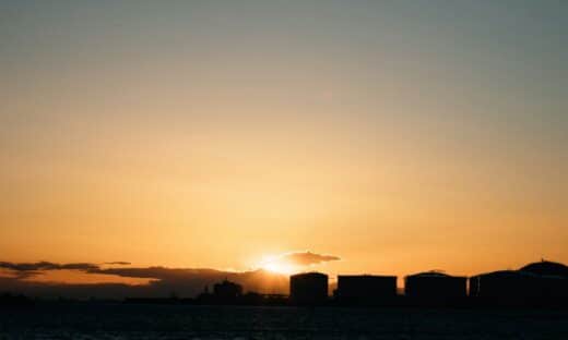 the sun is setting over a city on the water