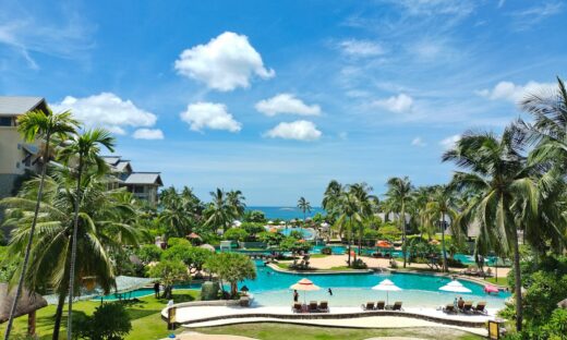 green palm trees near swimming pool under blue sky during daytime